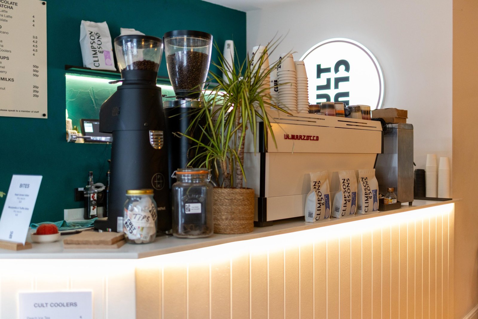 Counter with grinders and coffee bags lit from below at Cult Club Coffee