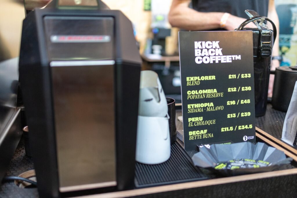 A Kickback Coffee menu board listing blends and prices beside a coffee grinder