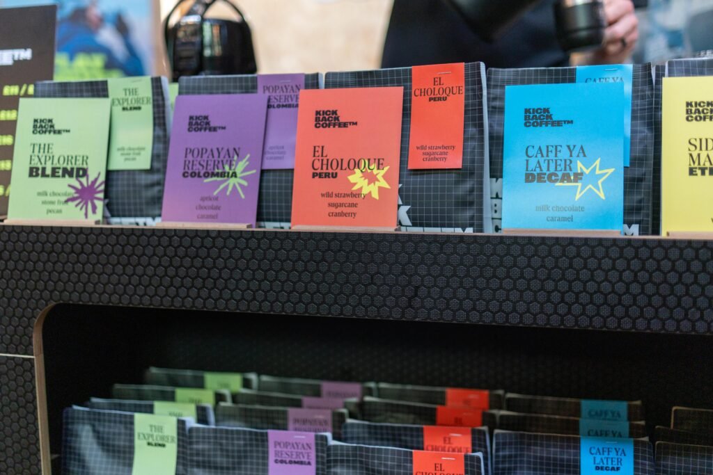 Colourful Kickback Coffee bags on a shelf, including The Explorer Blend, Popayan Reserve, El Choloque and a decaf