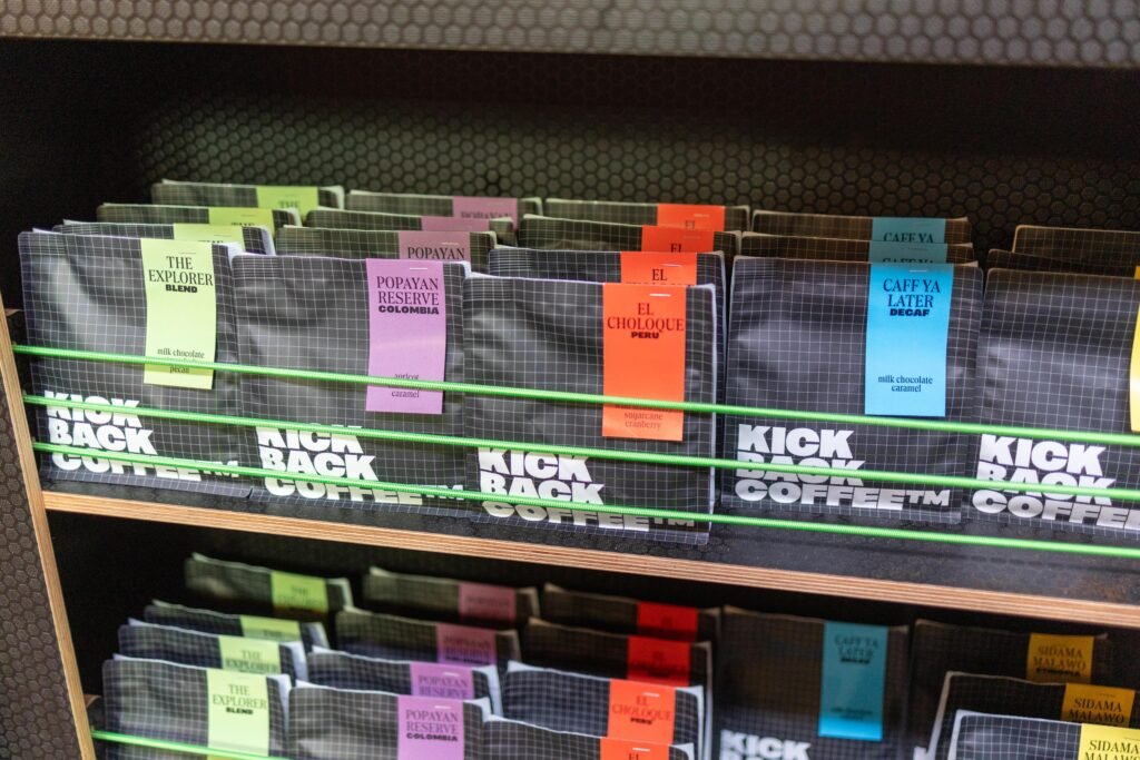 Shelves of dark Kickback Coffee bags with coloured labels for each coffee