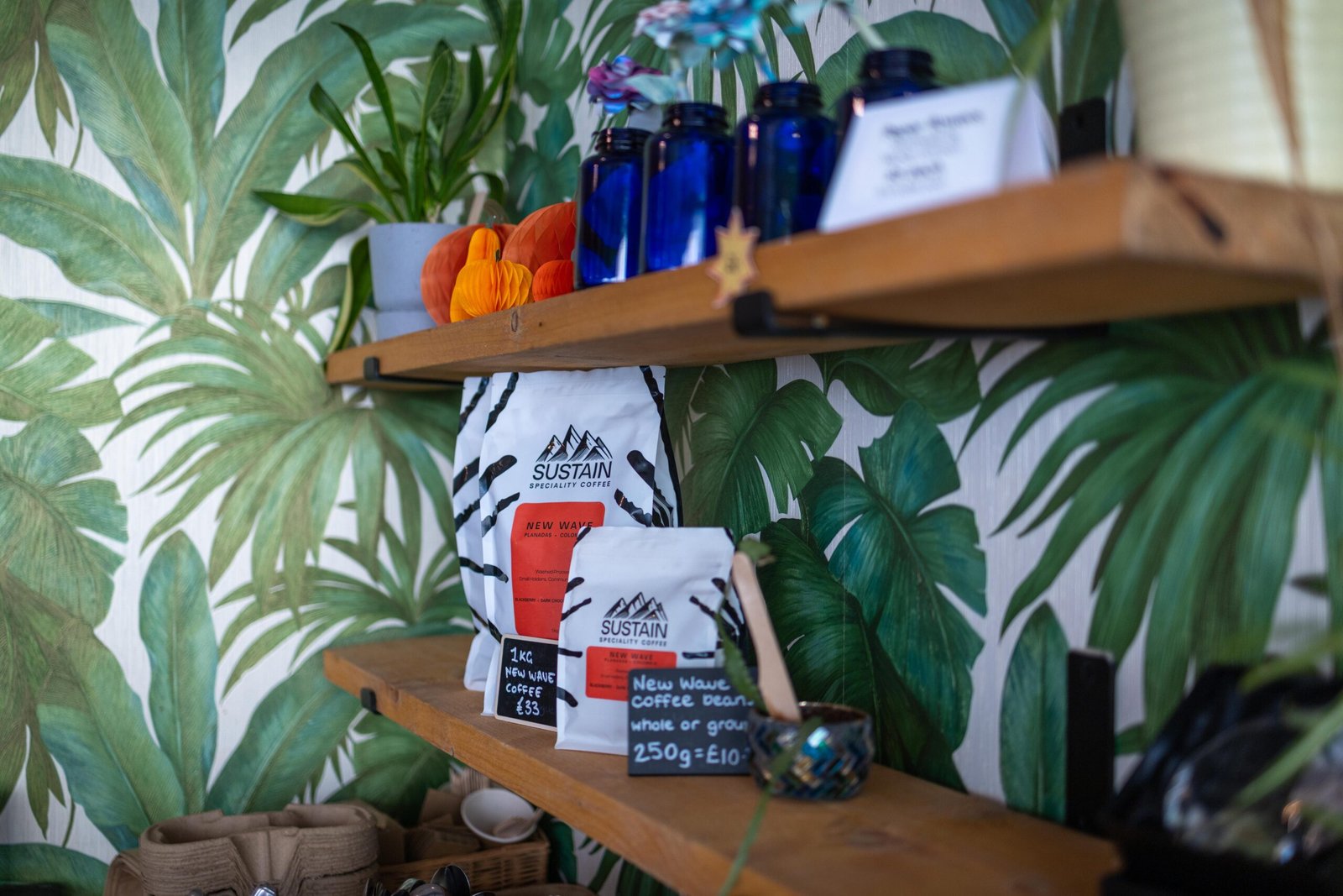 Shelves of coffee and gifts against palm-leaf wallpaper at Mudlarks Garden Cafe