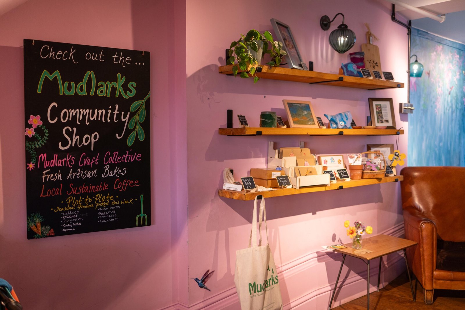 Chalkboard sign for the Mudlarks Community Shop beside shelves of local gifts