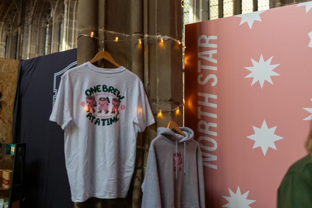 A North Star T-shirt and hoodie hanging against a pink wall with white stars
