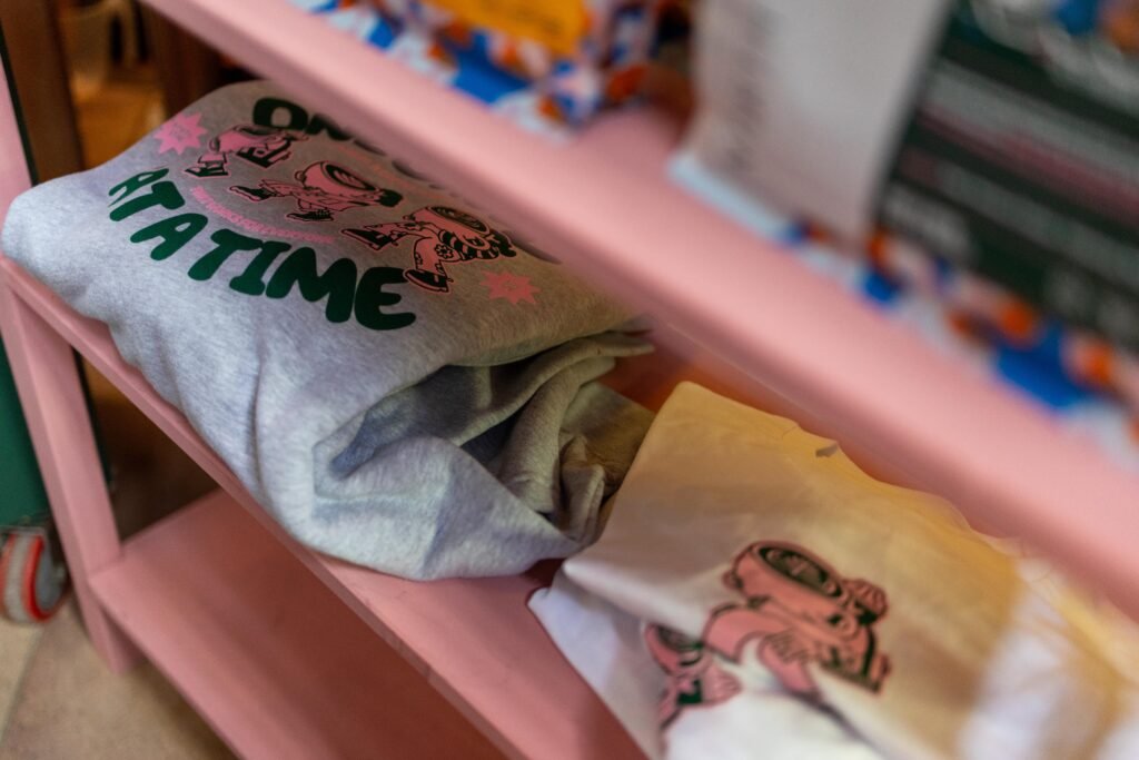 Folded North Star merchandise with printed designs on a pink shelf