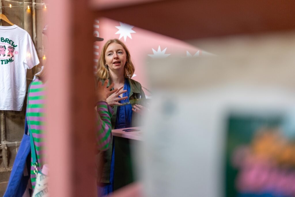 A North Star team member talking to a visitor, framed by pink shelves and merchandise