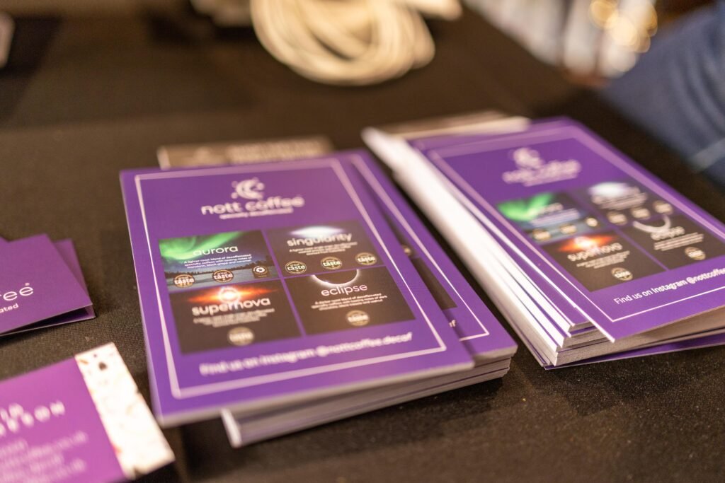 Purple Nott Coffee flyers fanned out on a black tablecloth