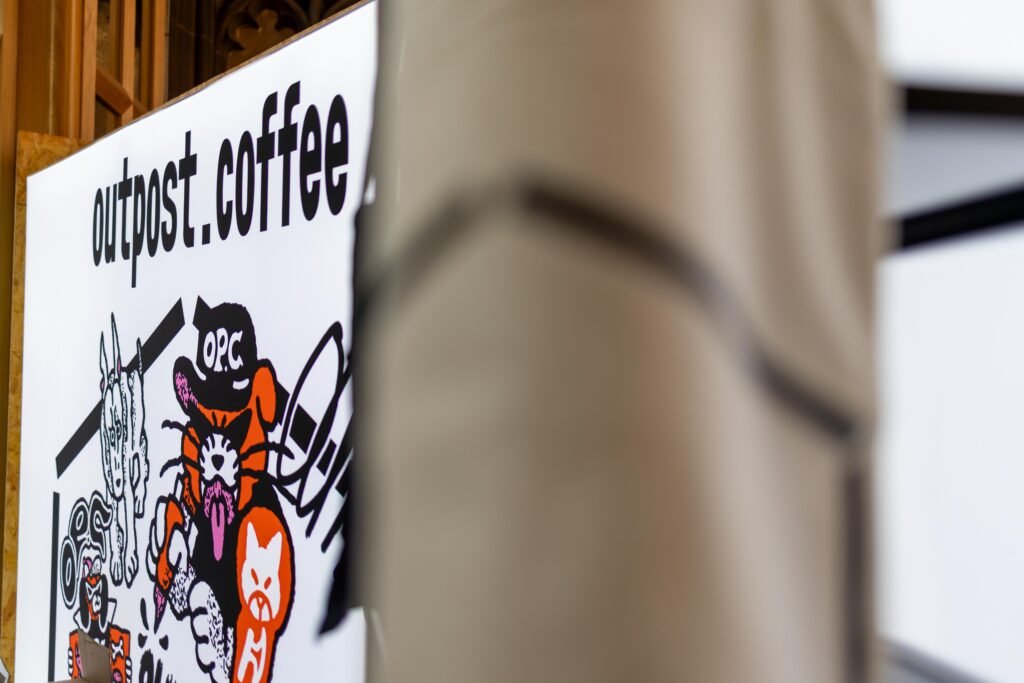 Outpost Coffee sign with a cartoon OPC character illustration
