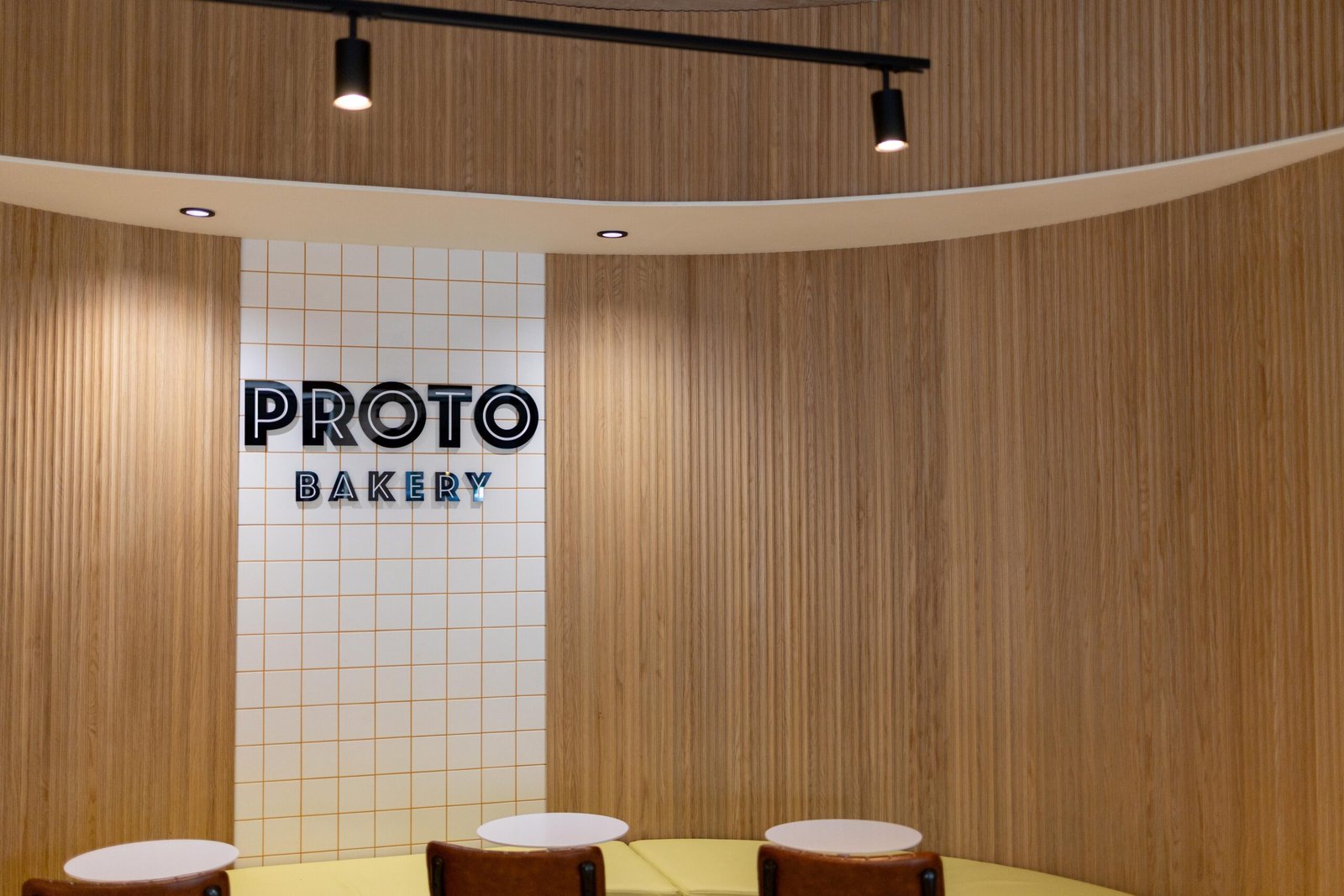 Proto Bakery logo on the wooden panelled wall inside the Hertford cafe