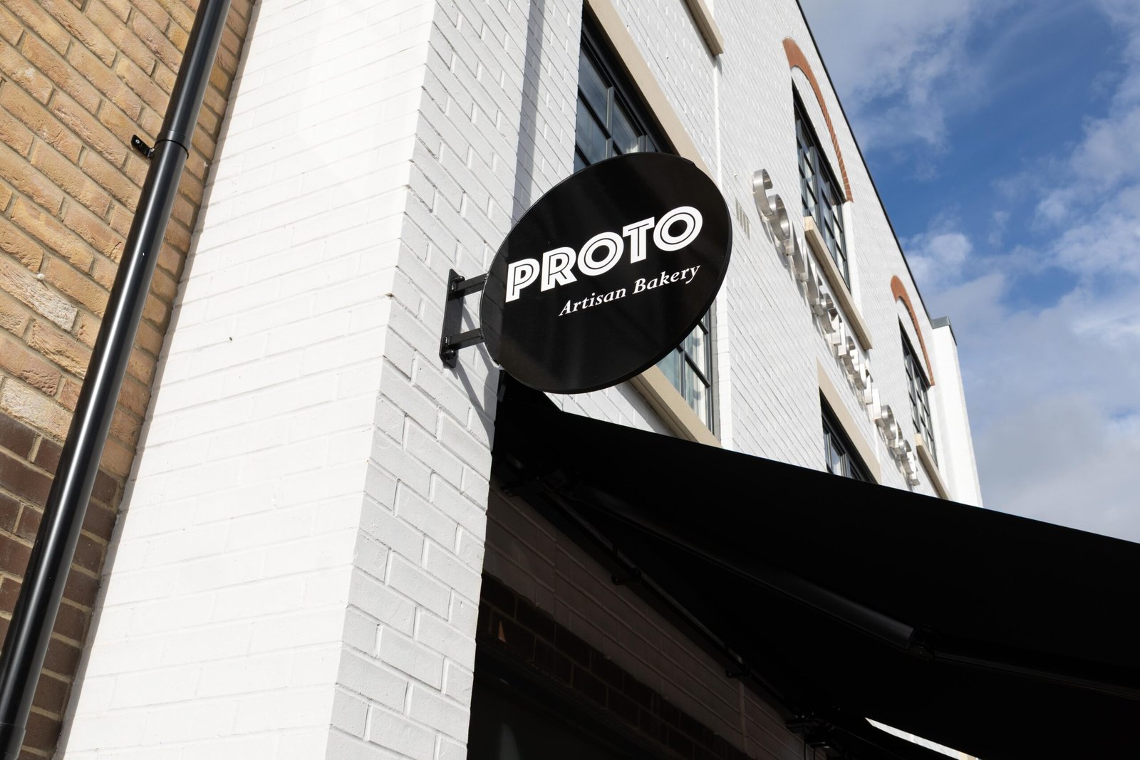 Proto Artisan Bakery black circular sign on its Hertford building