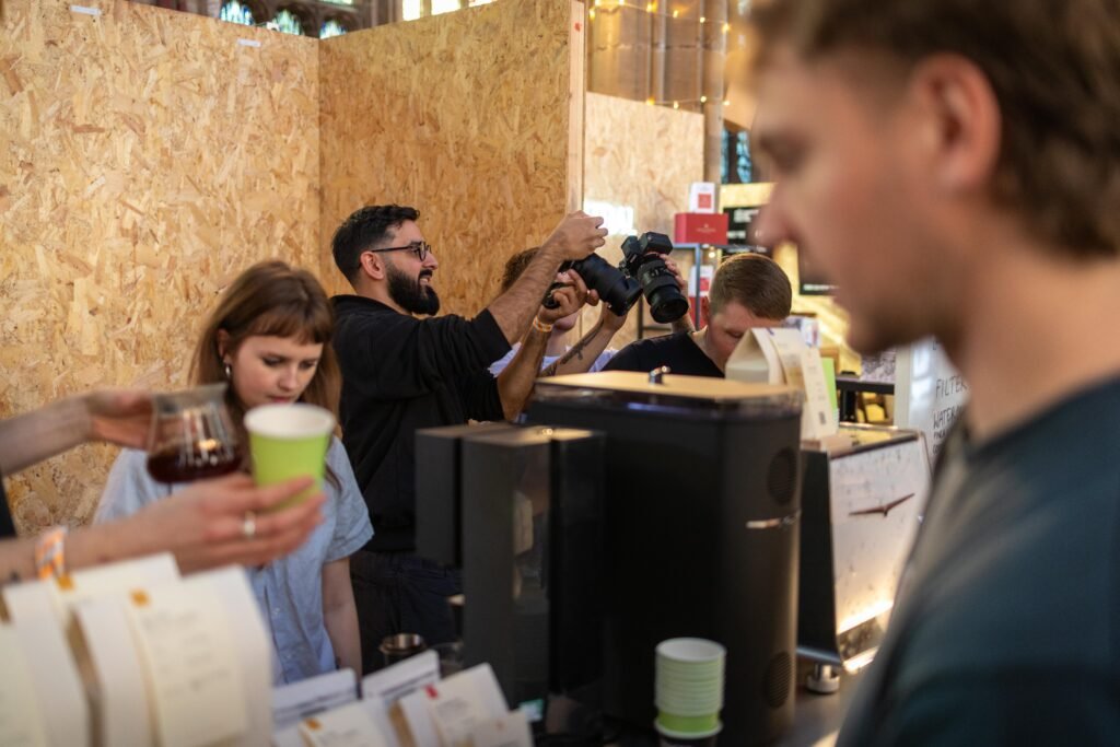 Saints of Mokha team members preparing coffee behind the counter, with a customer holding a green cup