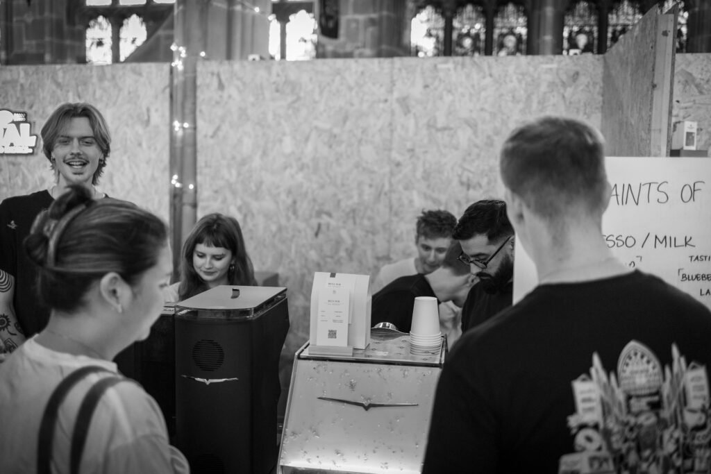 A black and white photo of Saints of Mokha team members serving customers at the stand