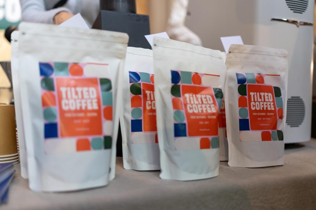 Tilted Coffee Roasters bags with orange and teal labels lined up on a table