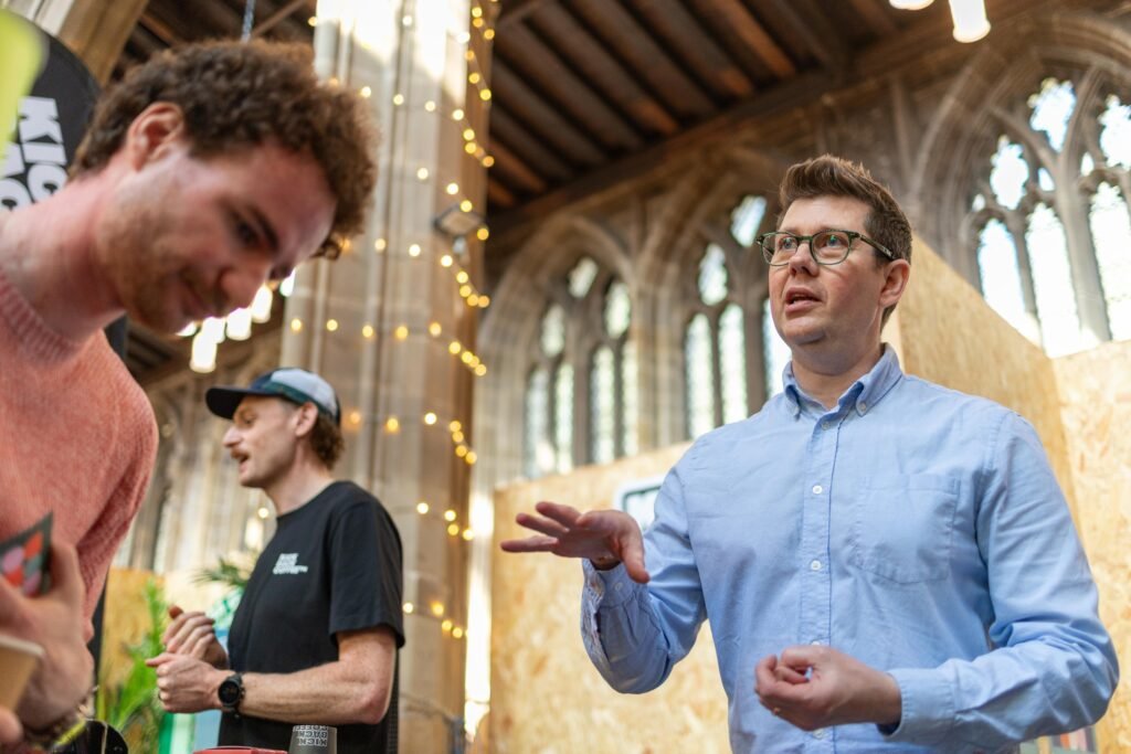 Tilted Coffee team member talking with visitors under the arched roof of St Mary's Church