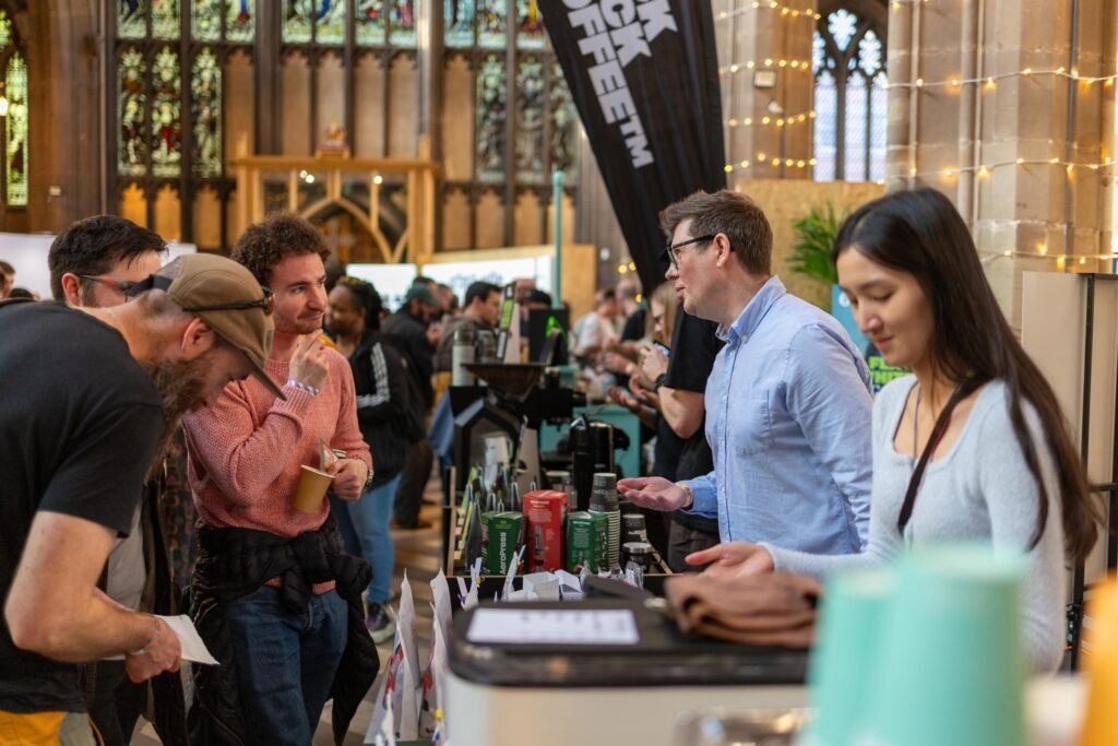 Visitors tasting coffee and chatting at a busy stand at Nottingham Coffee Festival